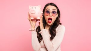 a woman excitedly holds up a piggy bank