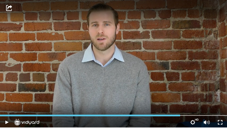 A screenshot of a Vidyard video featuring a male businessperson in a grey sweater