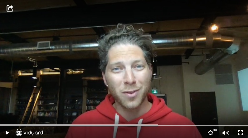 A screenshot of Vidyard CEO Michael Litt in a red sweater smiling at the camera