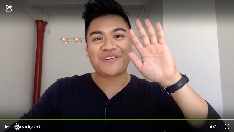 A screenshot of a Vidyard video featuring a smiling male salesperson waving at the camera