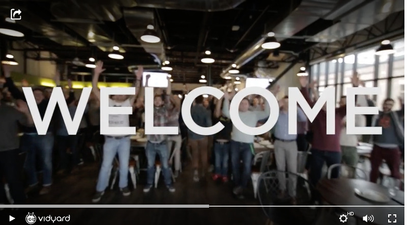 A screenshot of a Vidyard video featuring the Vidyard company team in the background with the word Welcome overlayed on the video