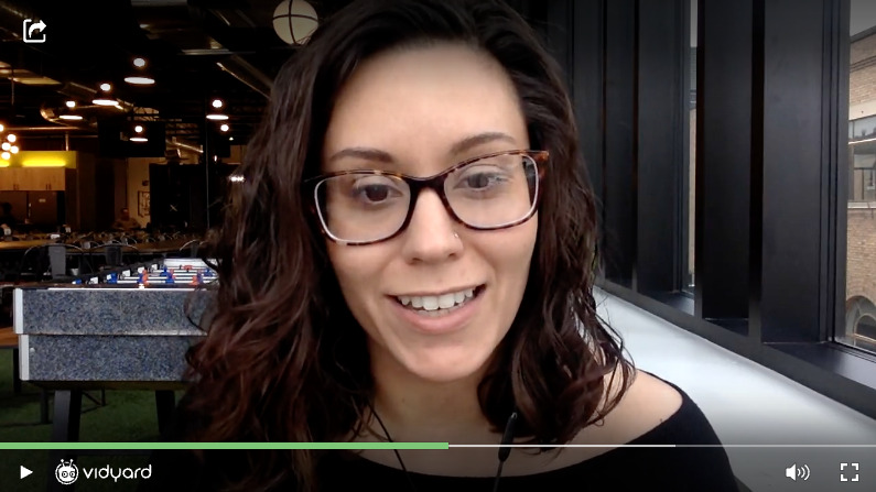 A screenshot of a Vidyard video featuring a smiling female customer success manager addressing the camera