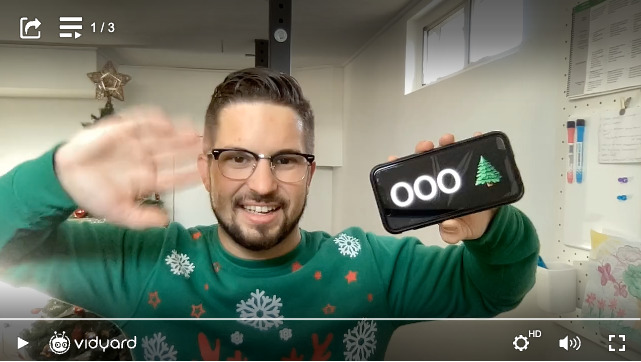 A sales rep in a Christmas sweater waving at the camera