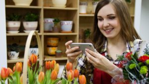 woman taking video of floral arrangement when video marketing for small businesses