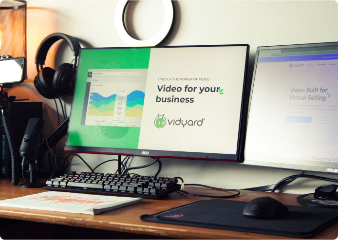 Home office desk with monitors displaying Vidyard website