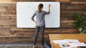 woman writes on a whiteboard while making an explainer video