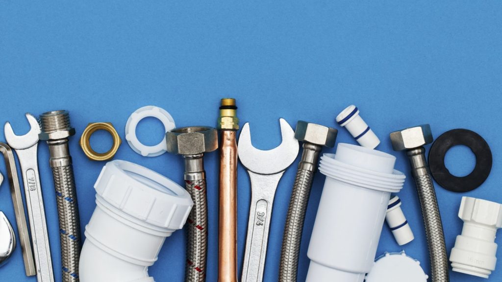 photo of pipes, wrenches, and other building supplies on a blue backdrop