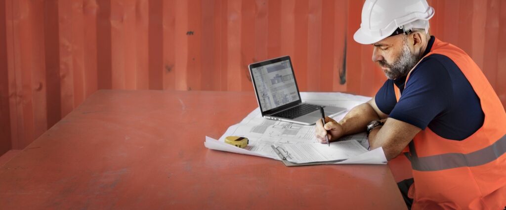 Photo of a man in a hard hat working on paperwork on a construction site