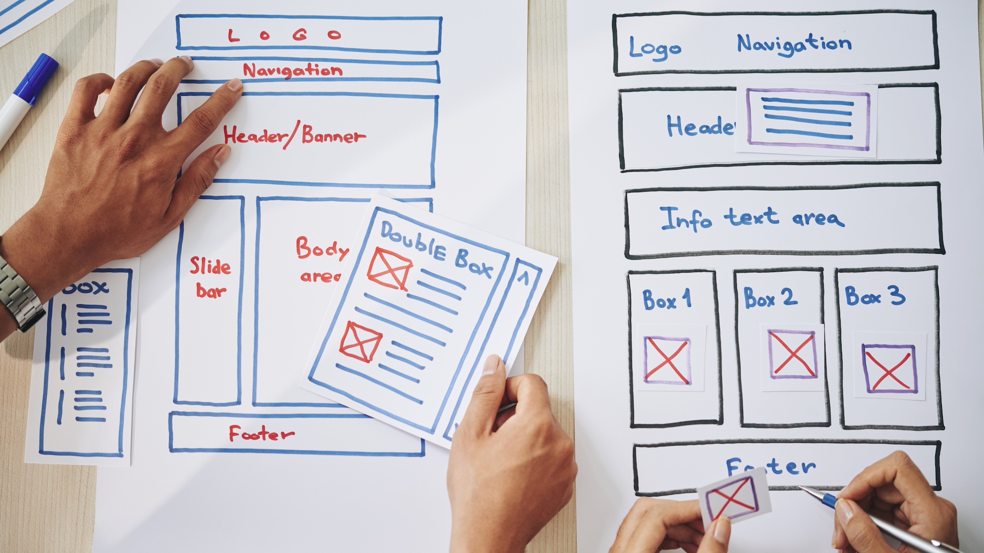 Two pairs of hands working on a paper version of a website layout